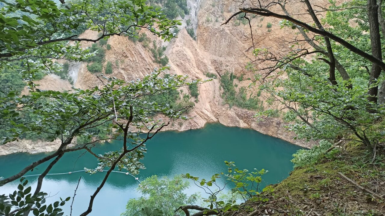 Smaragdno jezero u napuštenom kamenolomu, okruženo strmim odronima i šumom