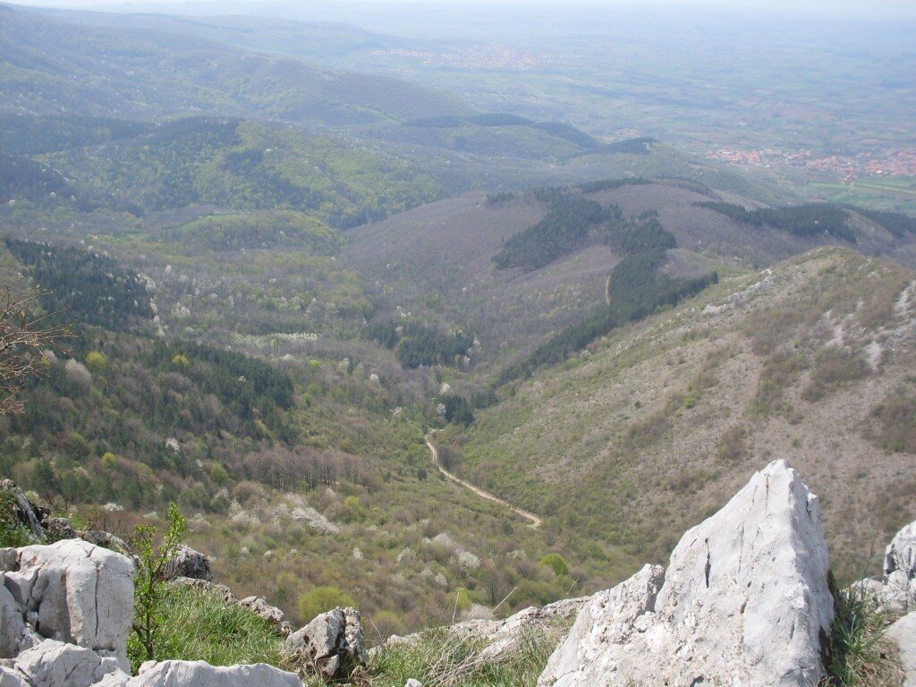 Pogled sa krečnjačkog grebena na doline i ravnicu sa selom u daljini