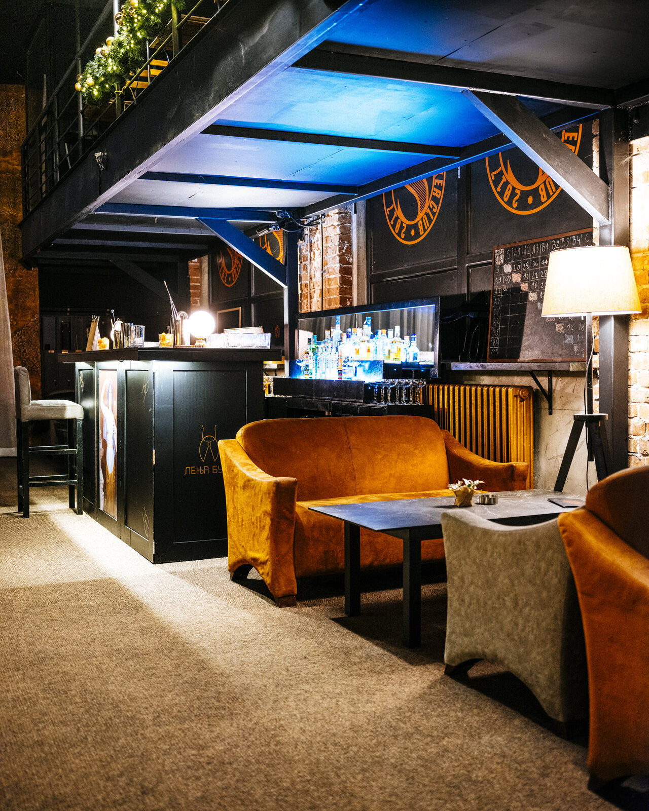 Lounge zona sa narandžastim somotskim sofama ispod galerije
